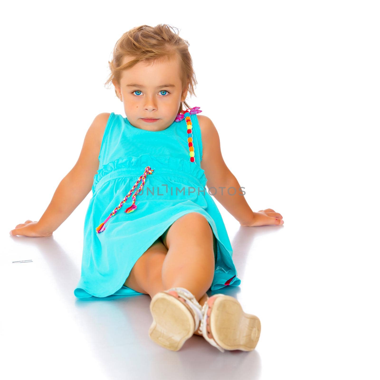 Beautiful little girl lies on the floor on a white background. The concept of a happy childhood, well-being in the family. Isolated.