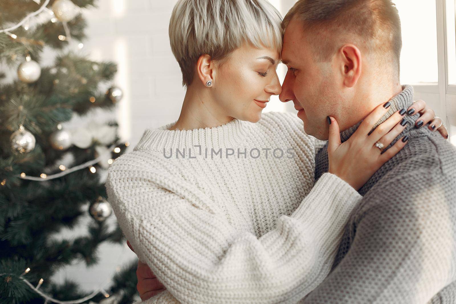 Family at home. Couple near christmas decorations. Woman in a gray sweater.