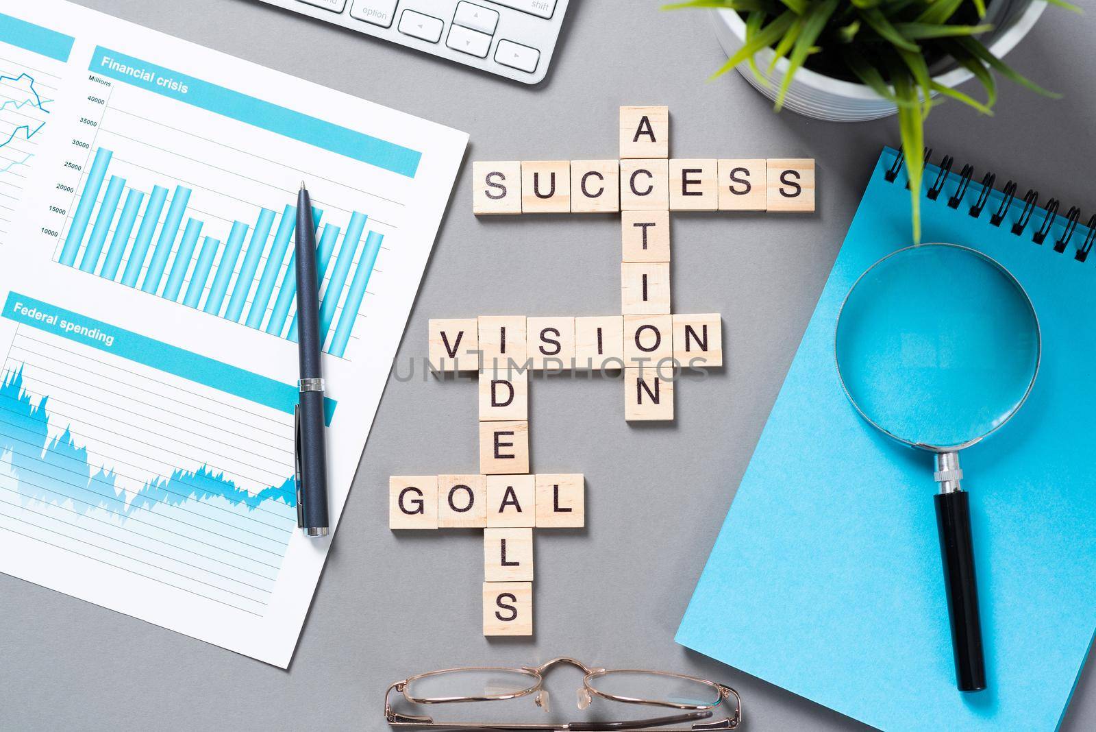 Business motivation concept with words from cubes. Still life of office workplace with crossword. Flat lay grey surface with magnifier and cup of coffee. New strategy planning and management