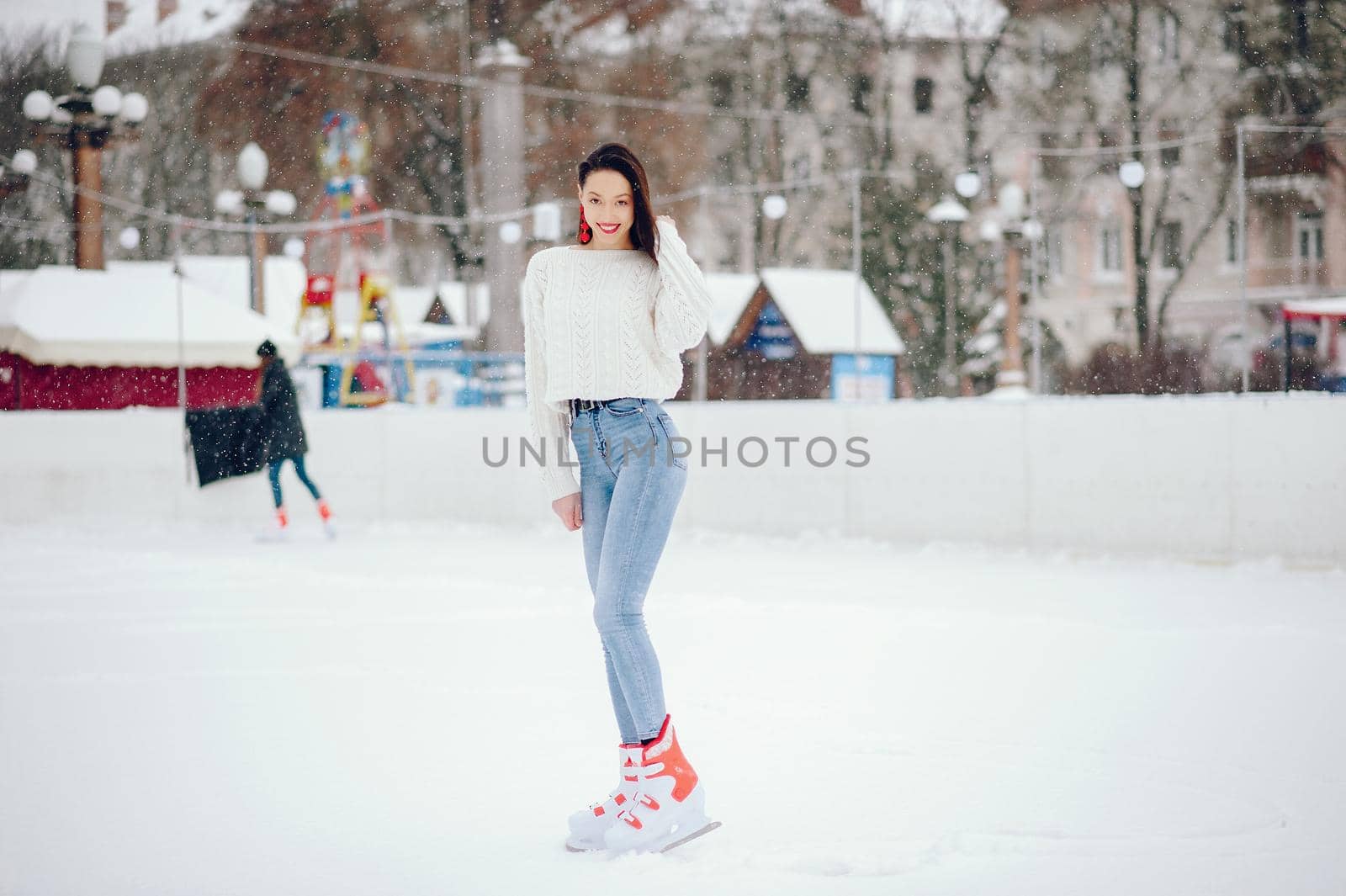 Girl in a winter city. Beautiful lady in a white sweater. Woman in a ice arena