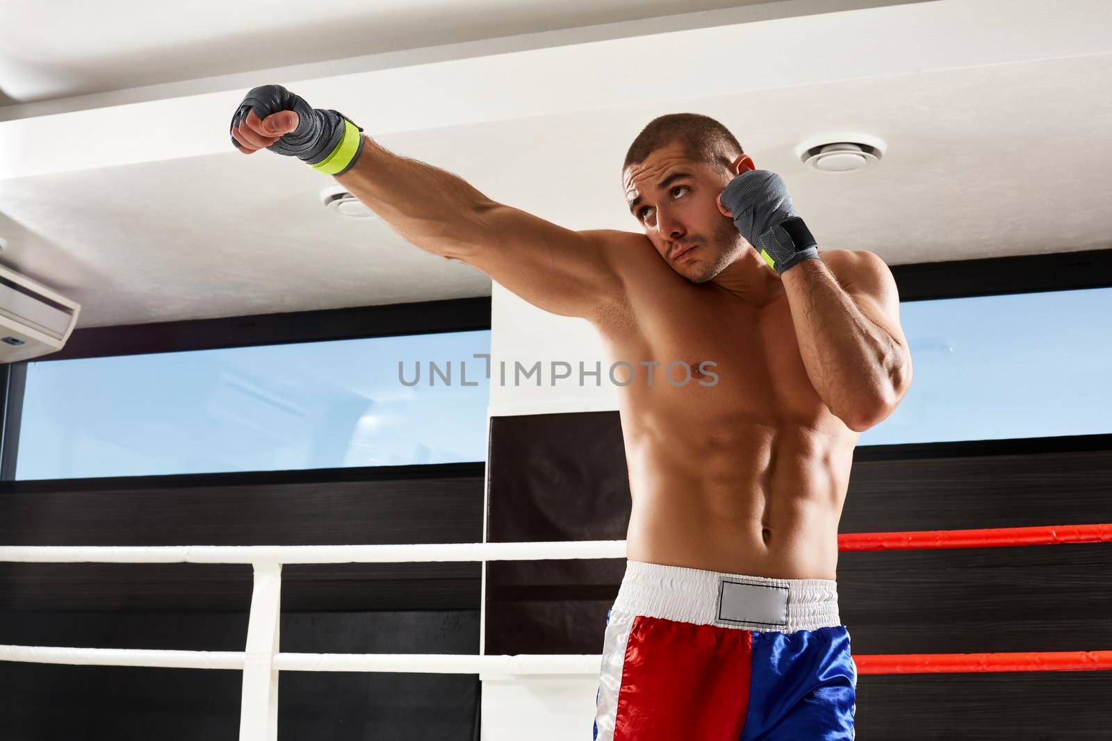 Boxer in grey gloves warming up in the gym. naked torso.