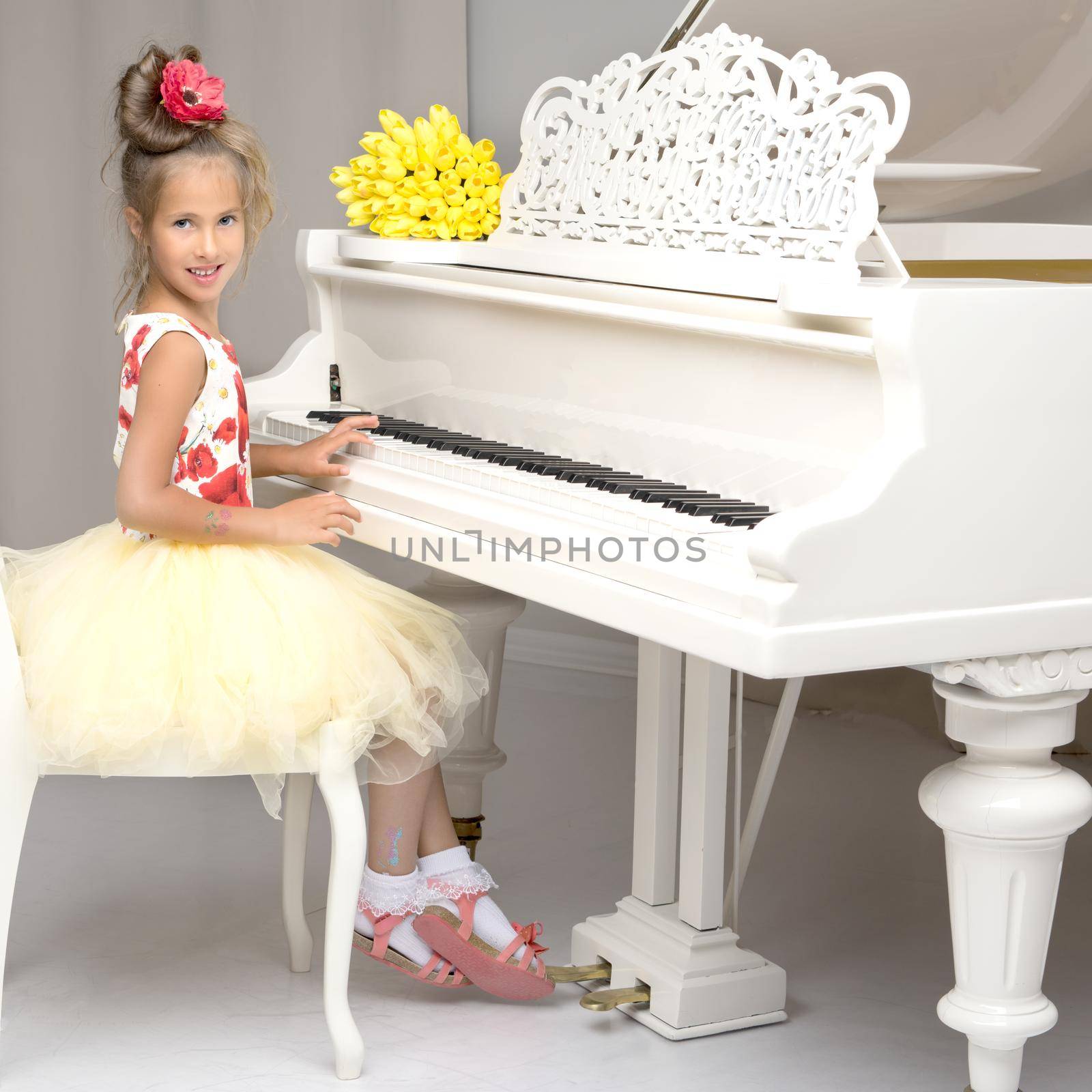 Beautiful little girl is playing on a white grand piano. by kolesnikov_studio