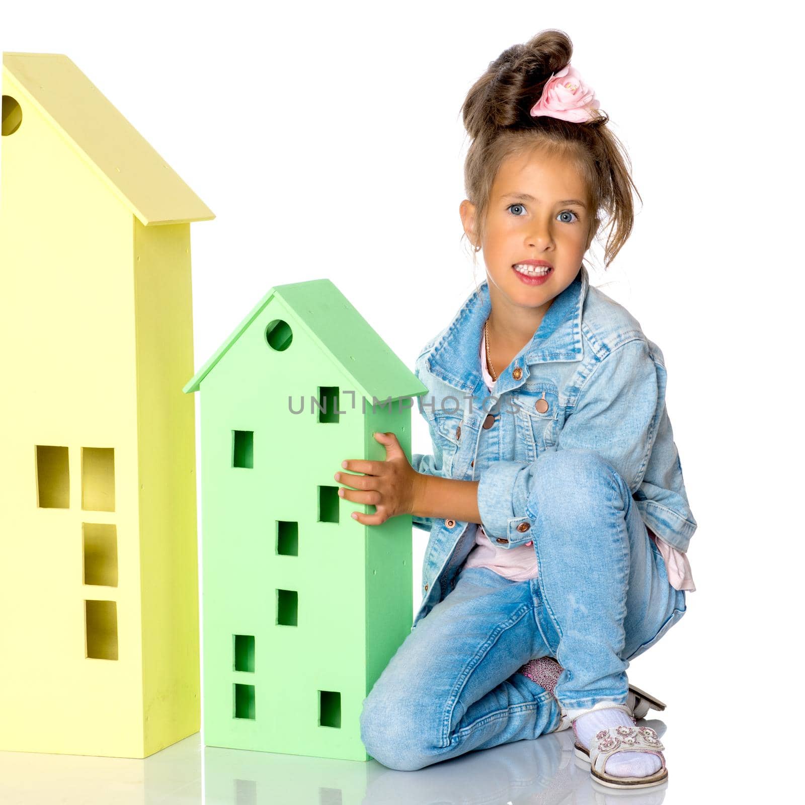 A cute little girl is playing with wooden houses. The concept of family happiness, play, creative development of the child.