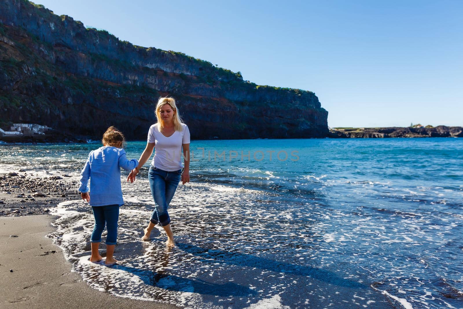 Family holiday on Tenerife, Spain. Mother with children outdoors on ocean. Portrait travel tourists - mom with kids. Positive human emotions, active lifestyles. Happy young family on sea beach by Andelov13