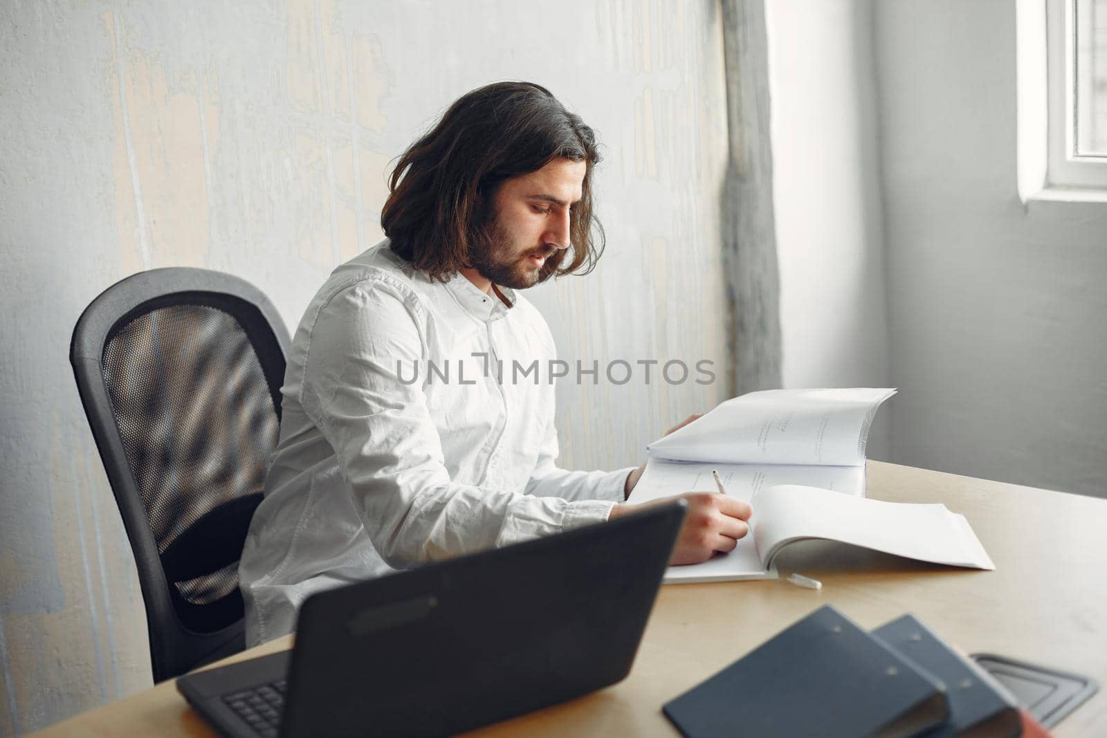 Handsome man in a white shirt. Businessman working at the office. Guy with a laptop.