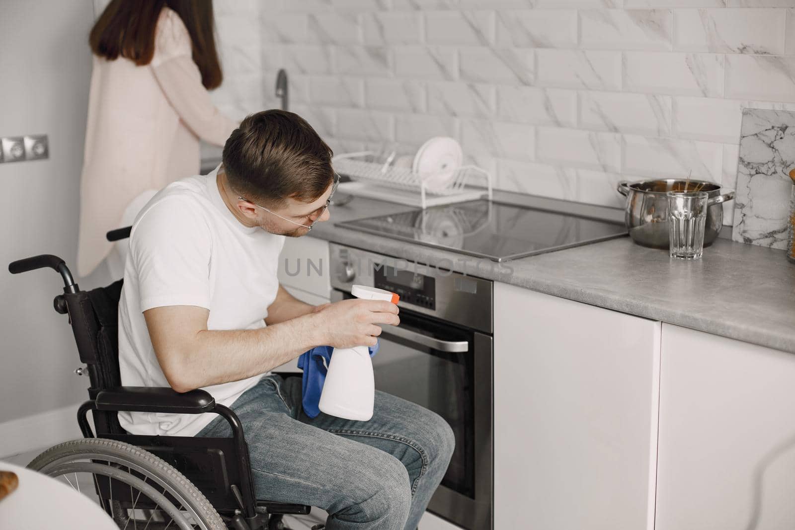 Disabled man cleaning the kitchen stove. Impaired people concept.