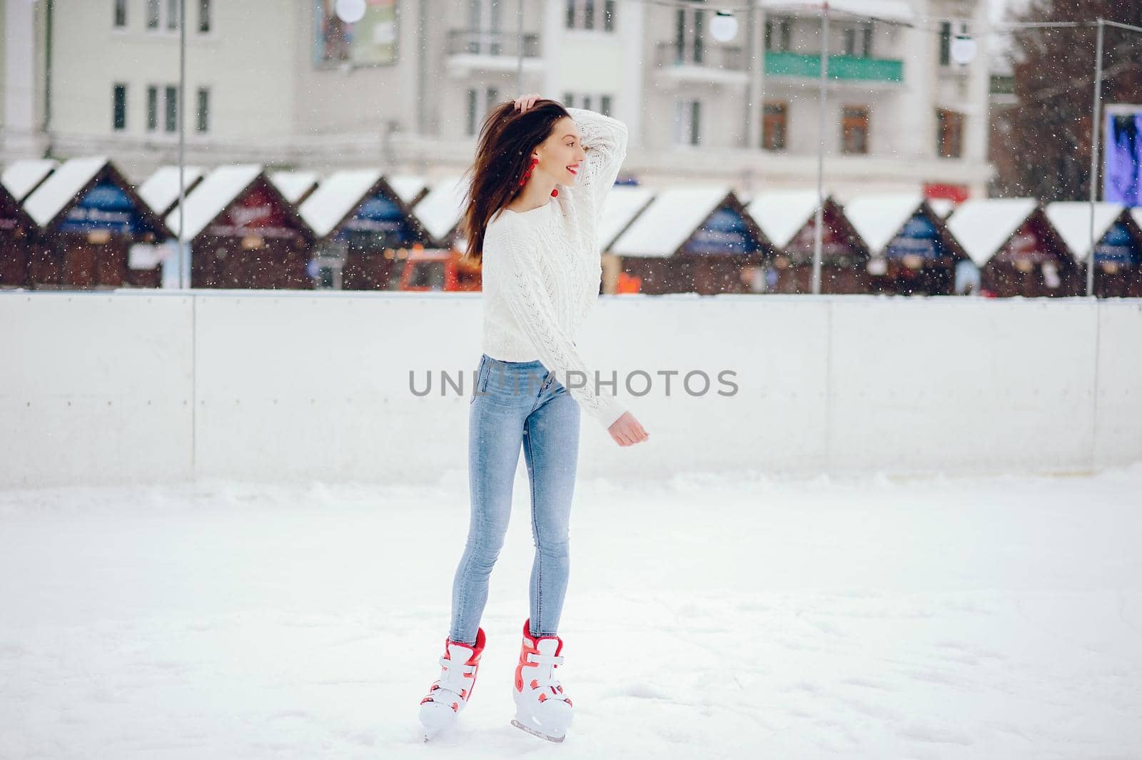 Girl in a winter city. Beautiful lady in a white sweater. Woman in a ice arena