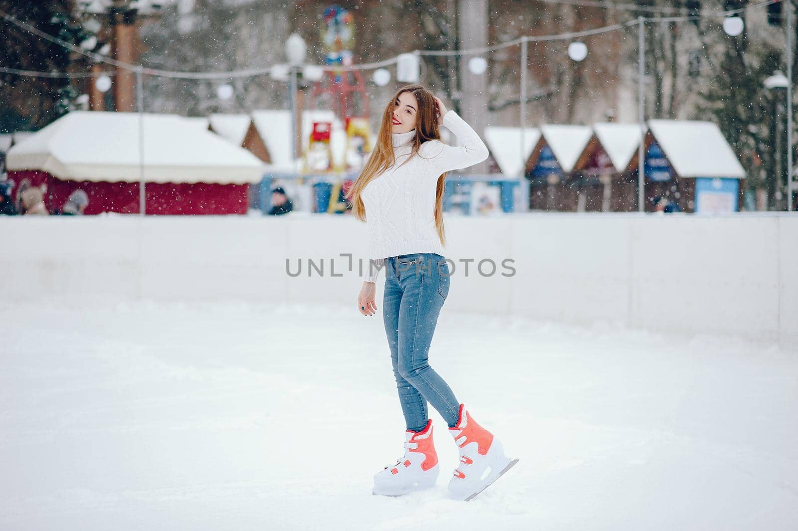 Girl in a winter city. Beautiful lady in a white sweater. Woman in a ice arena
