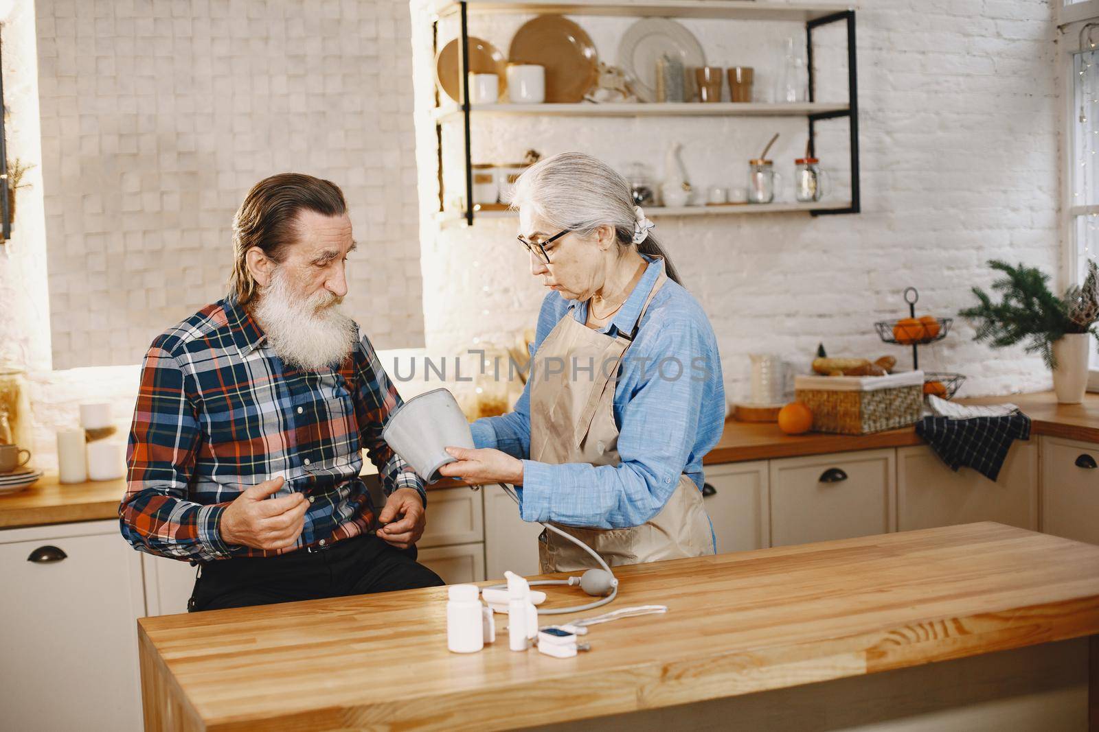 Old couple in a kitchen. Woman in a blue shirt and aprone.