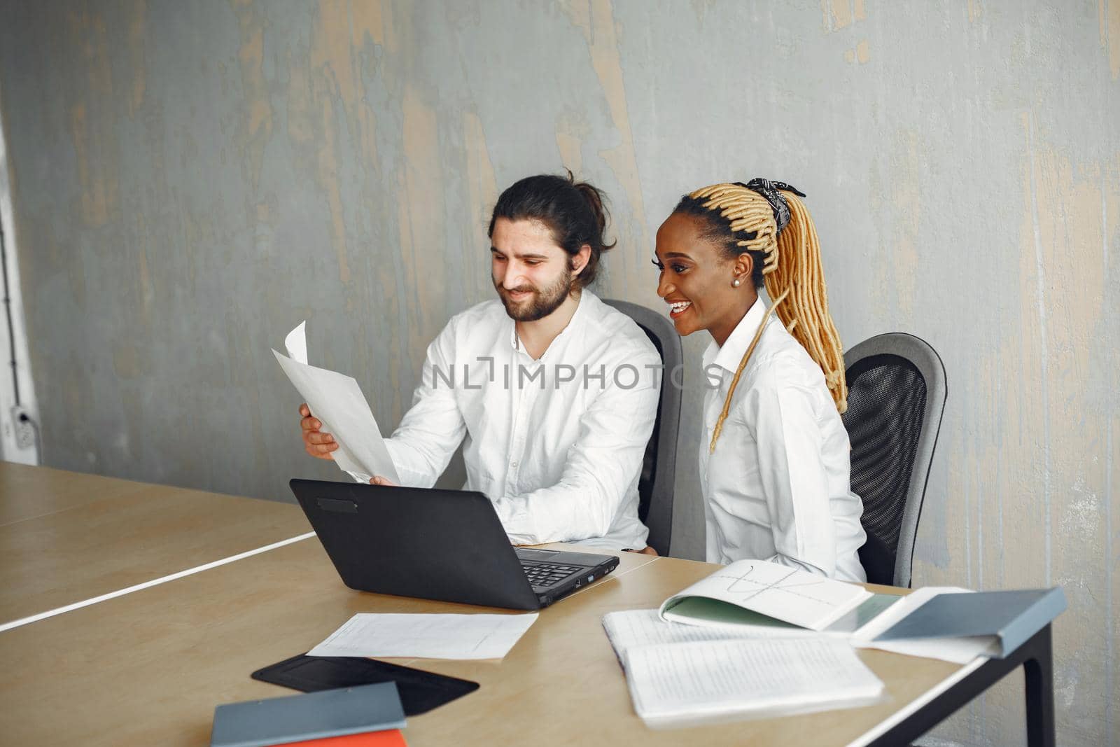 Handsome man in a white shirt. African woman with partner. Guy with a laptop.