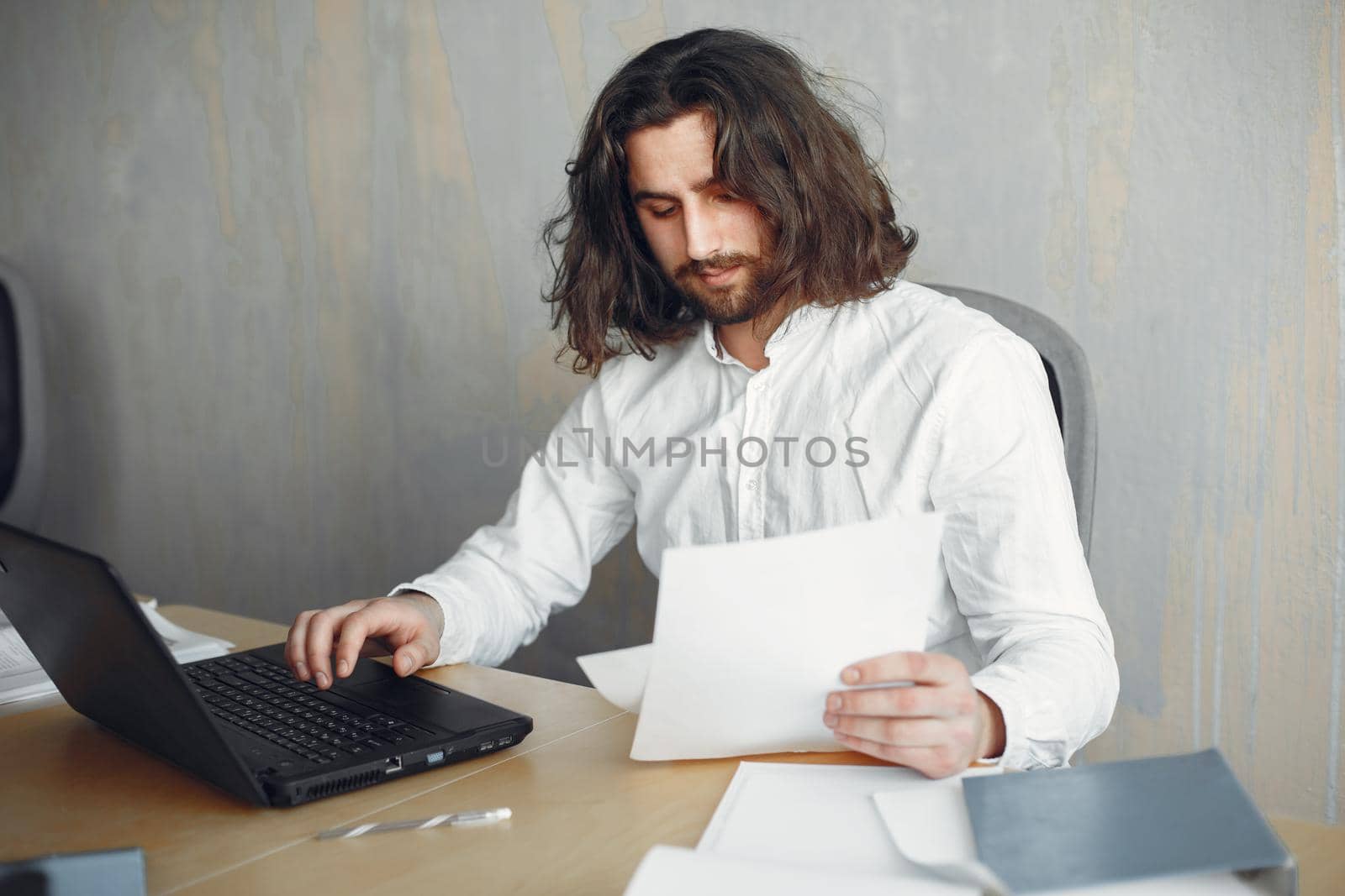 Handsome man in a white shirt. Businessman working at the office. Guy with a laptop.