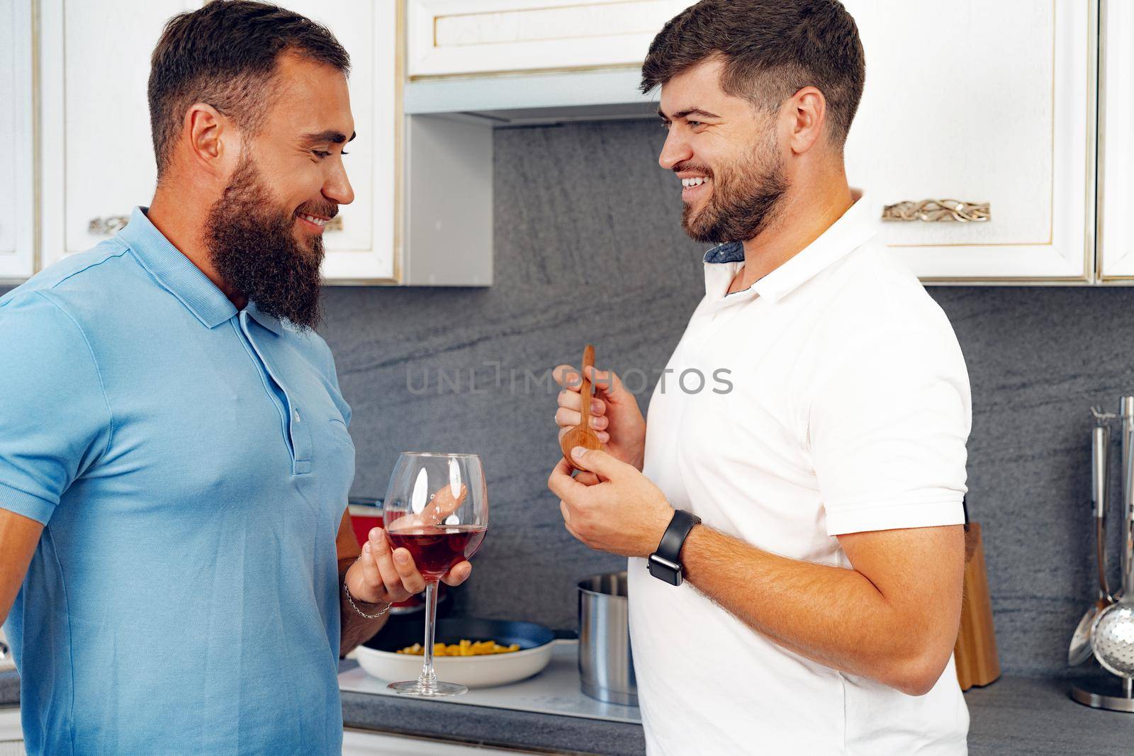 Happy homosexual couple preparing food together in kitchen at their house