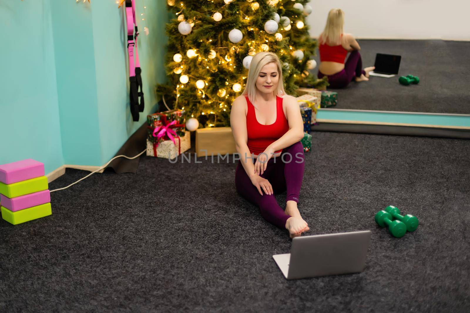 woman doing sports online on laptop on christmas vacation. New year's eve workout concept for stretching and yoga. Online training in the covid pandemic.