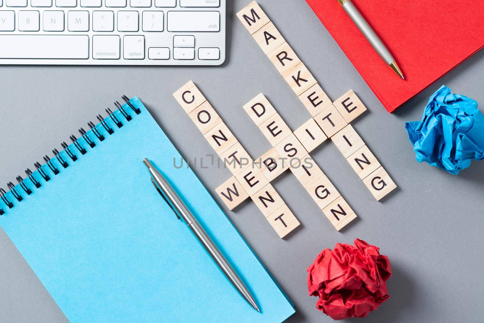 Web marketing concept with words from cubes. Still life of office workplace with crossword. Flat lay grey surface with pc keyboard and notebook. New strategy planning and workflow optimization.