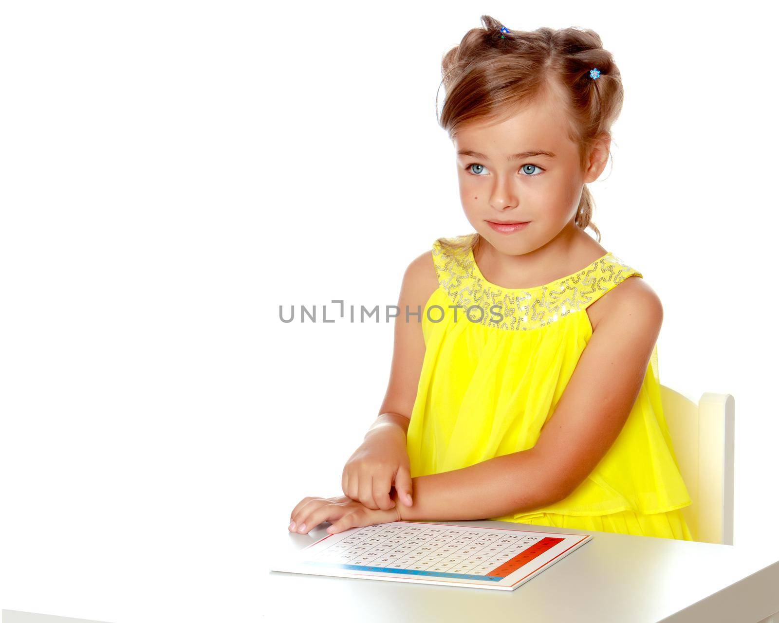 A little girl in Montessori kindergarten sits at a table and studies Montessori stuff. The concept of school and preschool education, harmonious development of the child. Isolated on white background.