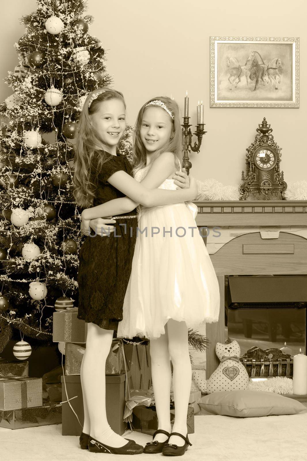 Adorable little twin girls hugging each other near the Christmas tree.Black-and-white photo. Retro style.