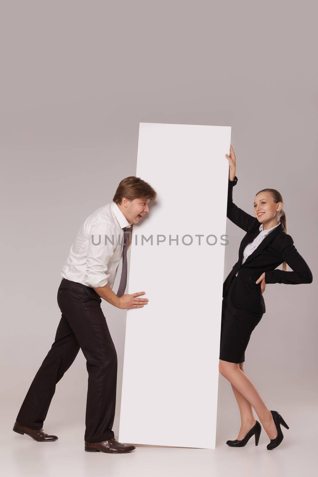 Business man and woman standing on both sides of blank banner the man pushing the banner. isolated on grey background. Teamwork concept