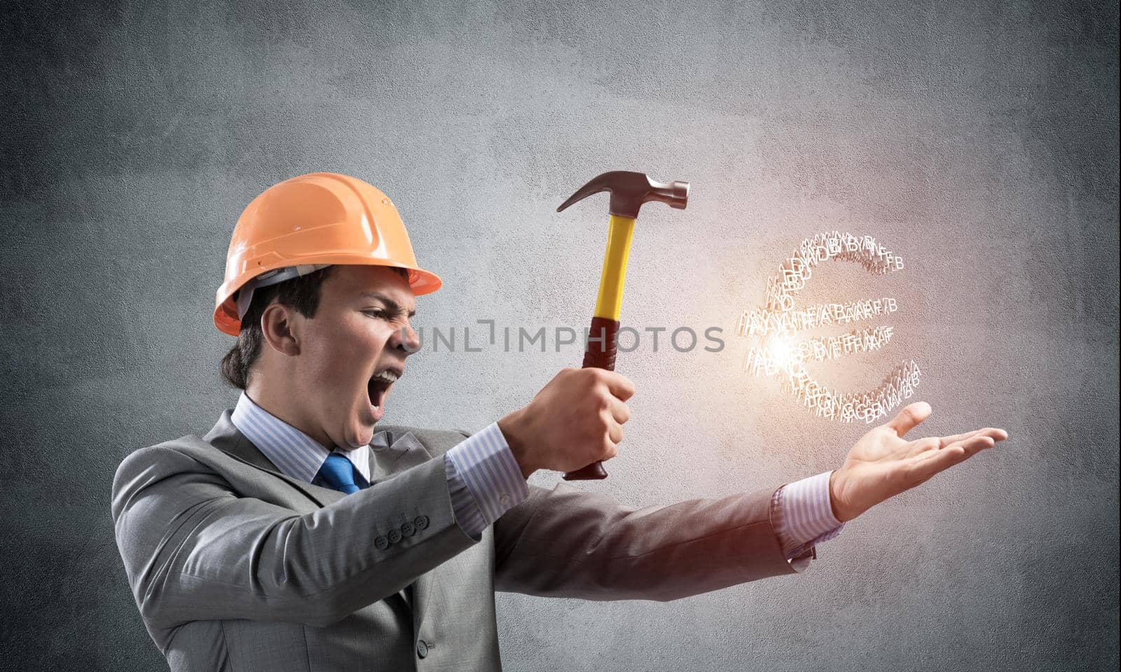 Furious businessman going to crash with hammer euro currency sign. Handsome man in business suit and safety helmet standing on grey wall background. Financial crisis, bankruptcy and inflation pressure