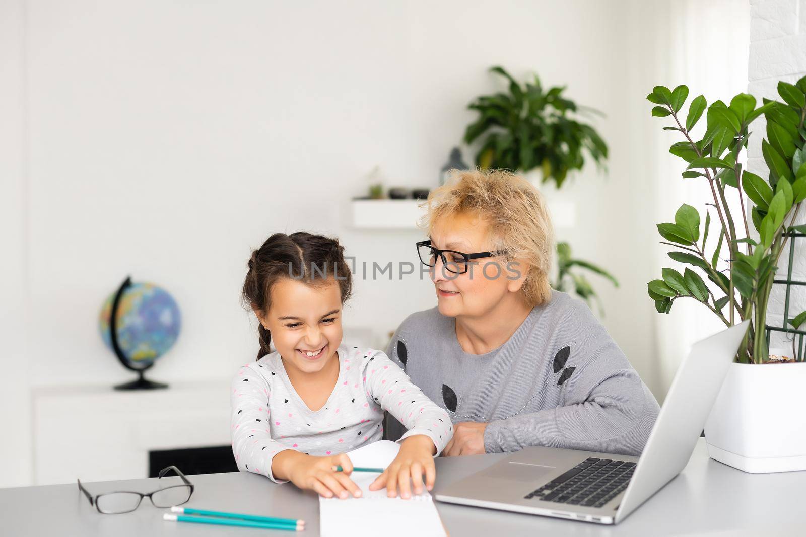 Helpful granny. Helpful loving granny assisting her cute granddaughter making homework by Andelov13