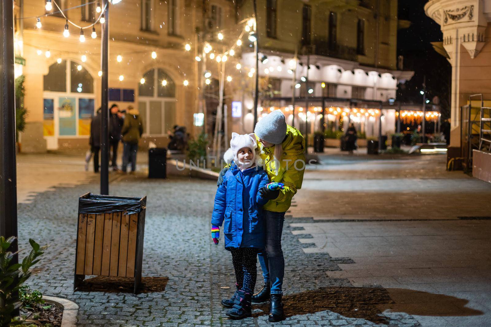 Mother with child girl at Christmas market celebrating New Year holiday. Family outdoor winter activity. Mom and daughter spend time together. Authentic lifestyle. by Andelov13