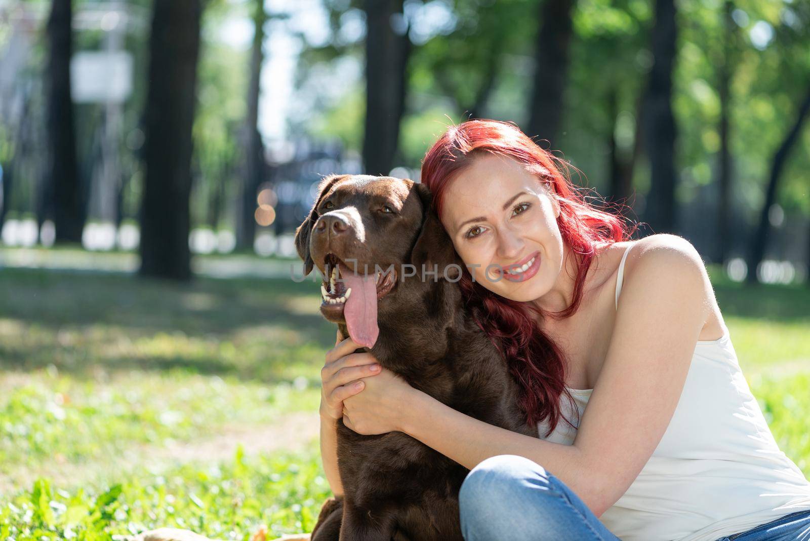 Young attractive woman hugs her dog in the park. by adam121