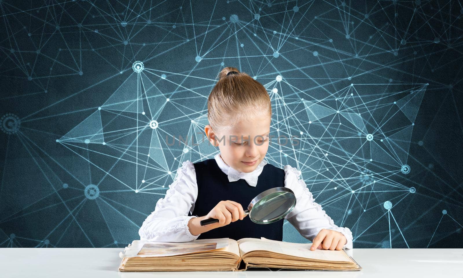 Little girl sitting at desk with magnifier and open book. Research and education in school. Happy schoolgirl in school wear carefully studying book. Clever girl reading book with magnifying glass.