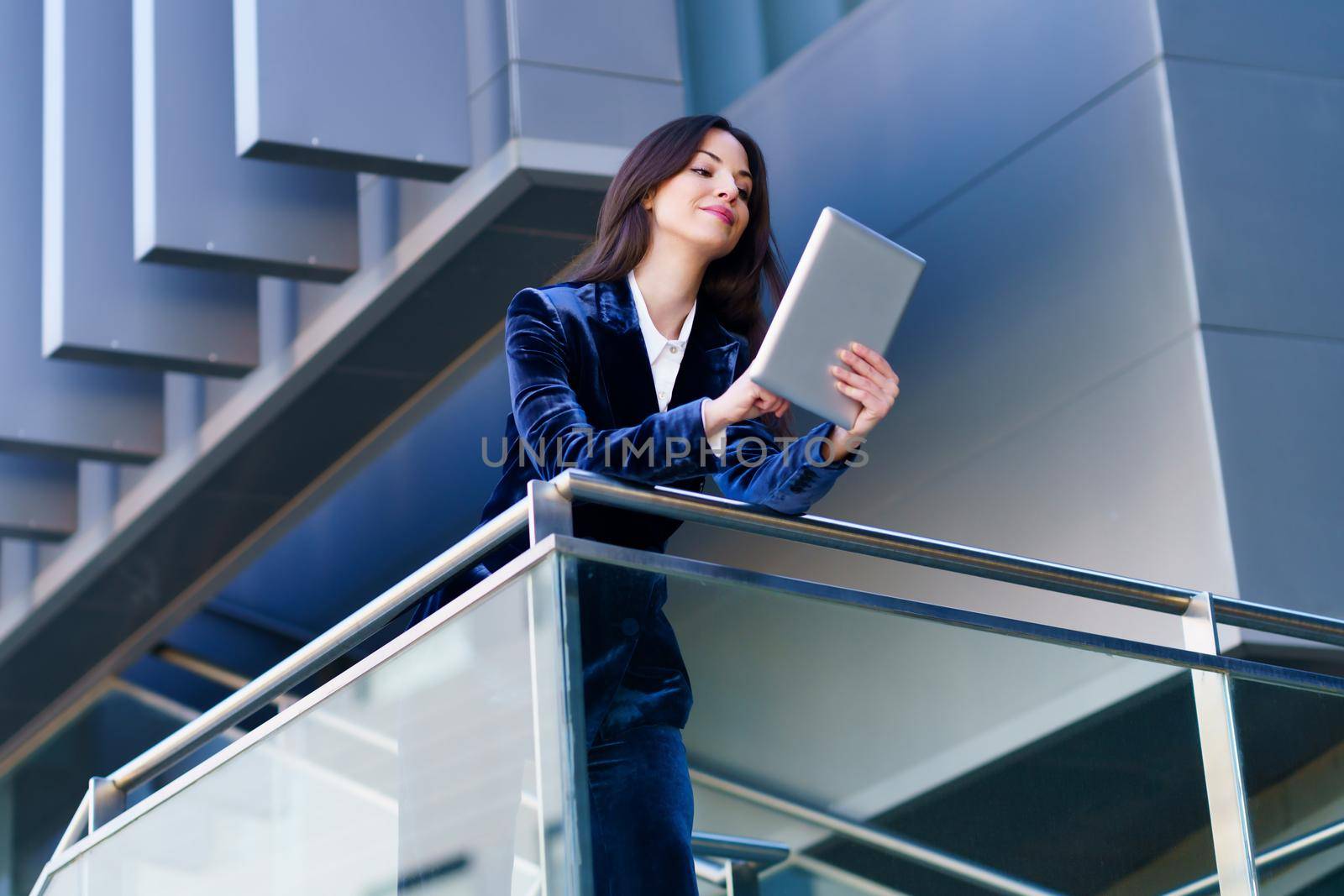 Business woman wearing blue suit using digital tablet in an office building. by javiindy