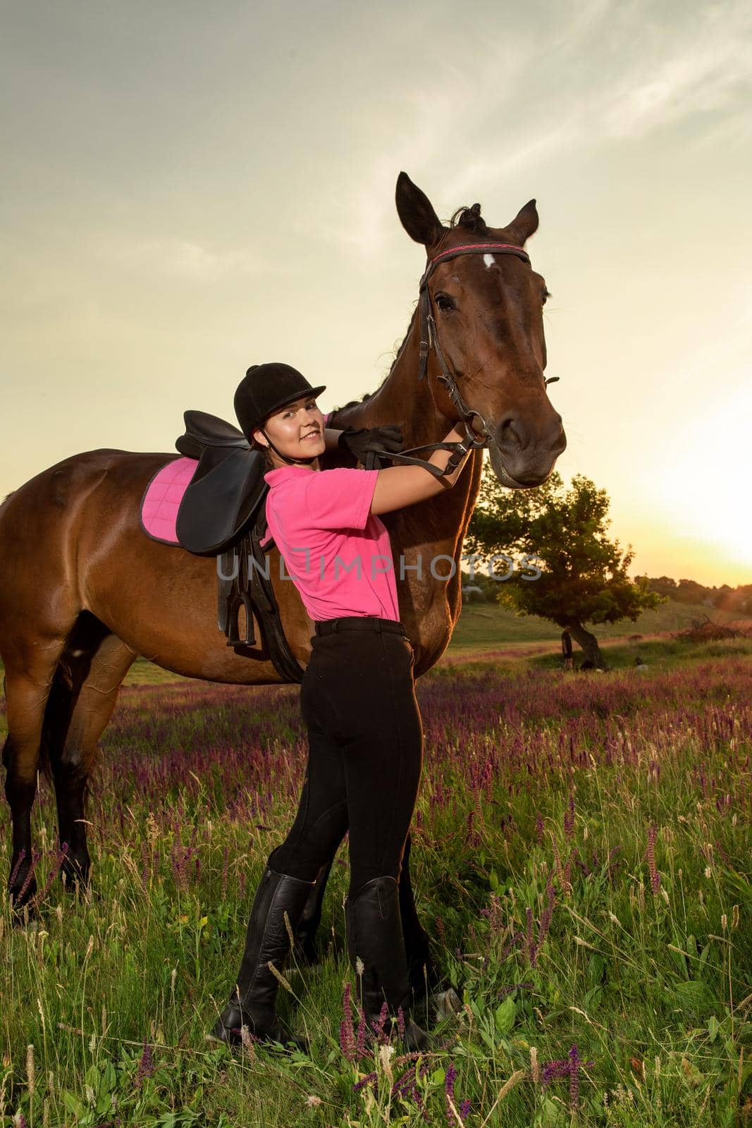 Beautiful young girl smile at her horse dressing uniform competition: outdoors portrait on sunset. Taking care of animals, love and friendship concept.