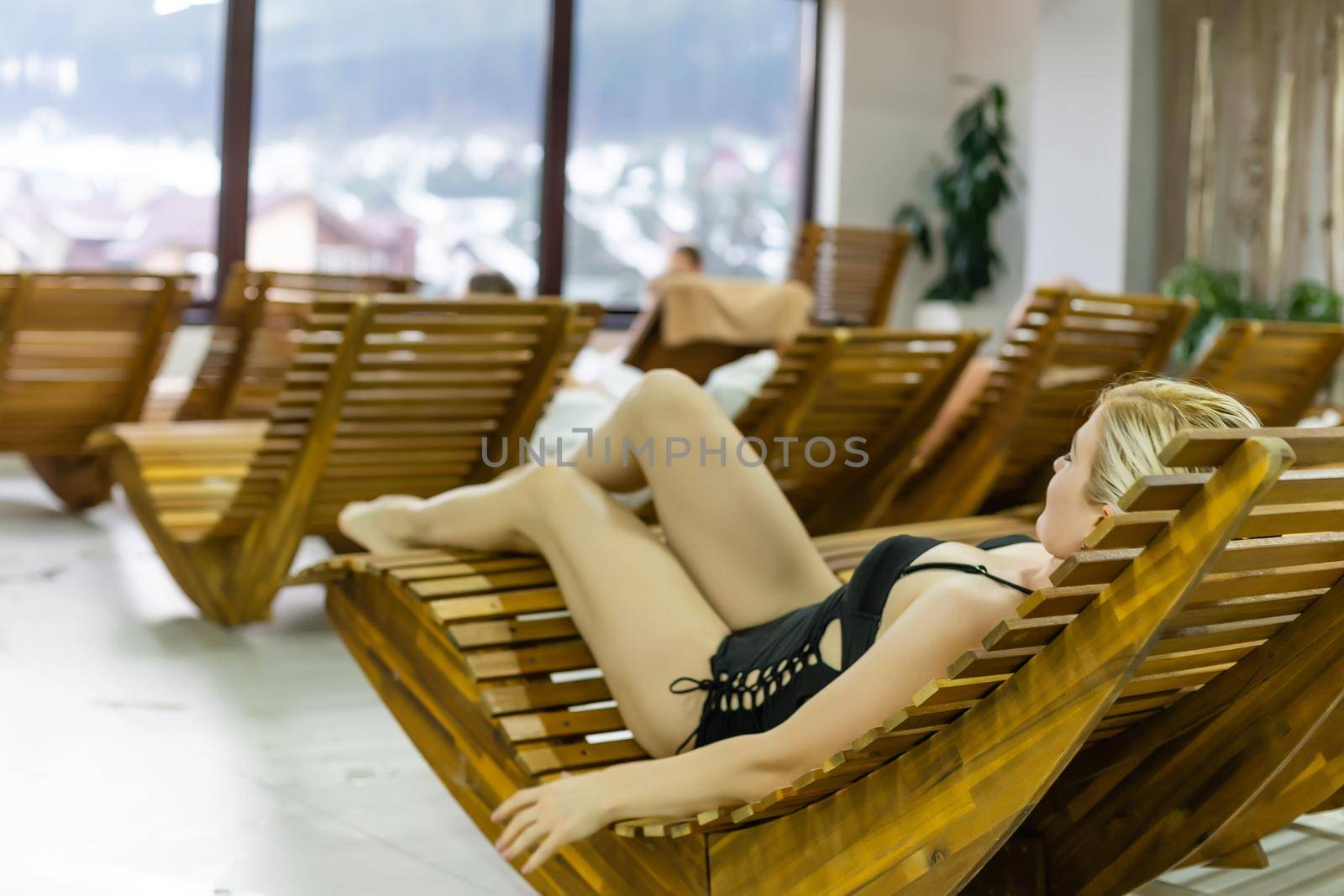 Portrait of beautiful adult Caucasian woman relaxing in luxury indoors near the swimming pool in resort hotel