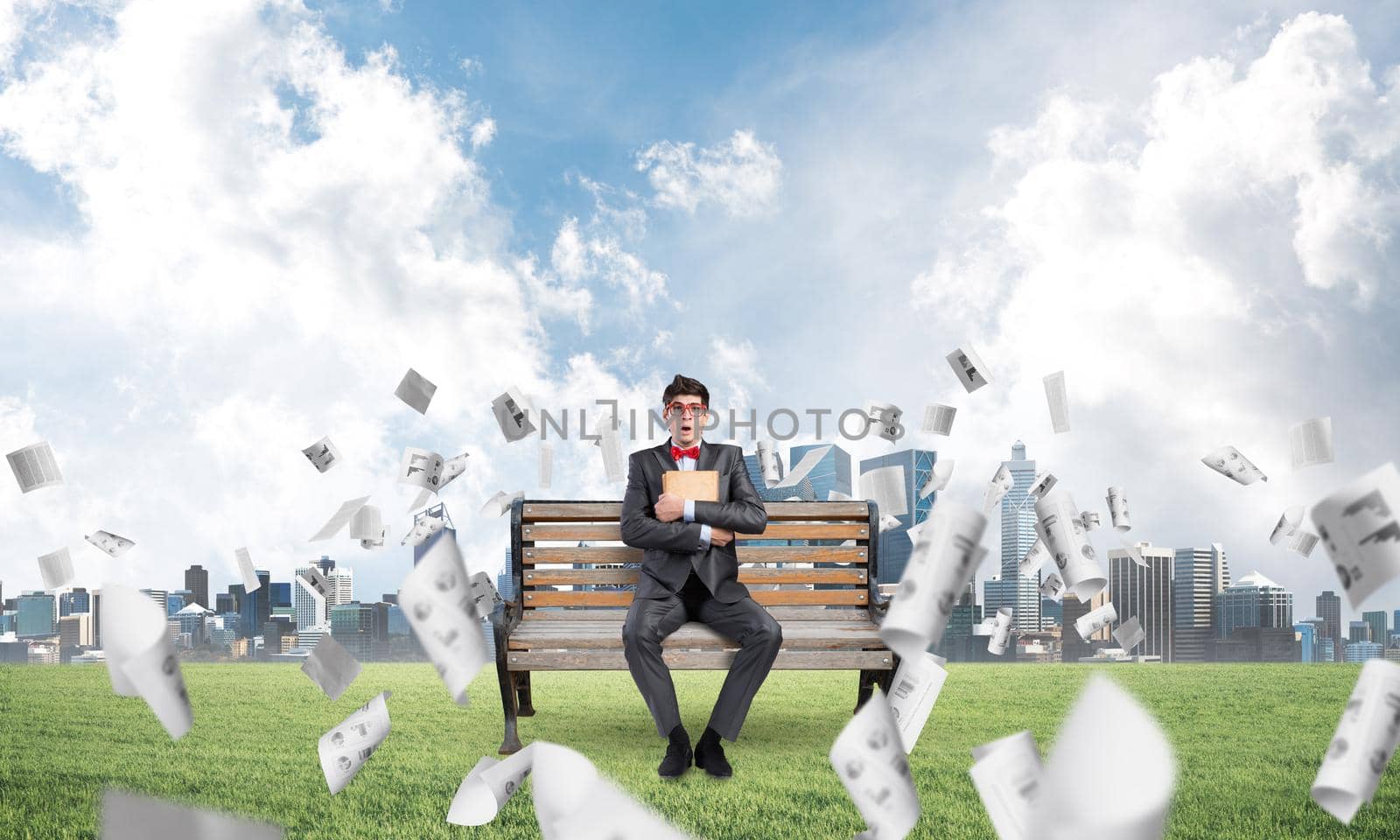 a young student sits on a bench and squeezes the book, looks up
