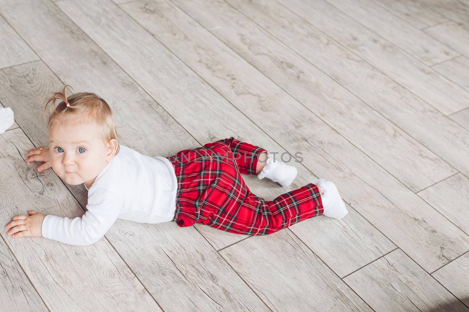 Little cute baby in pretty sleepwear lies on the white floor by StudioLucky