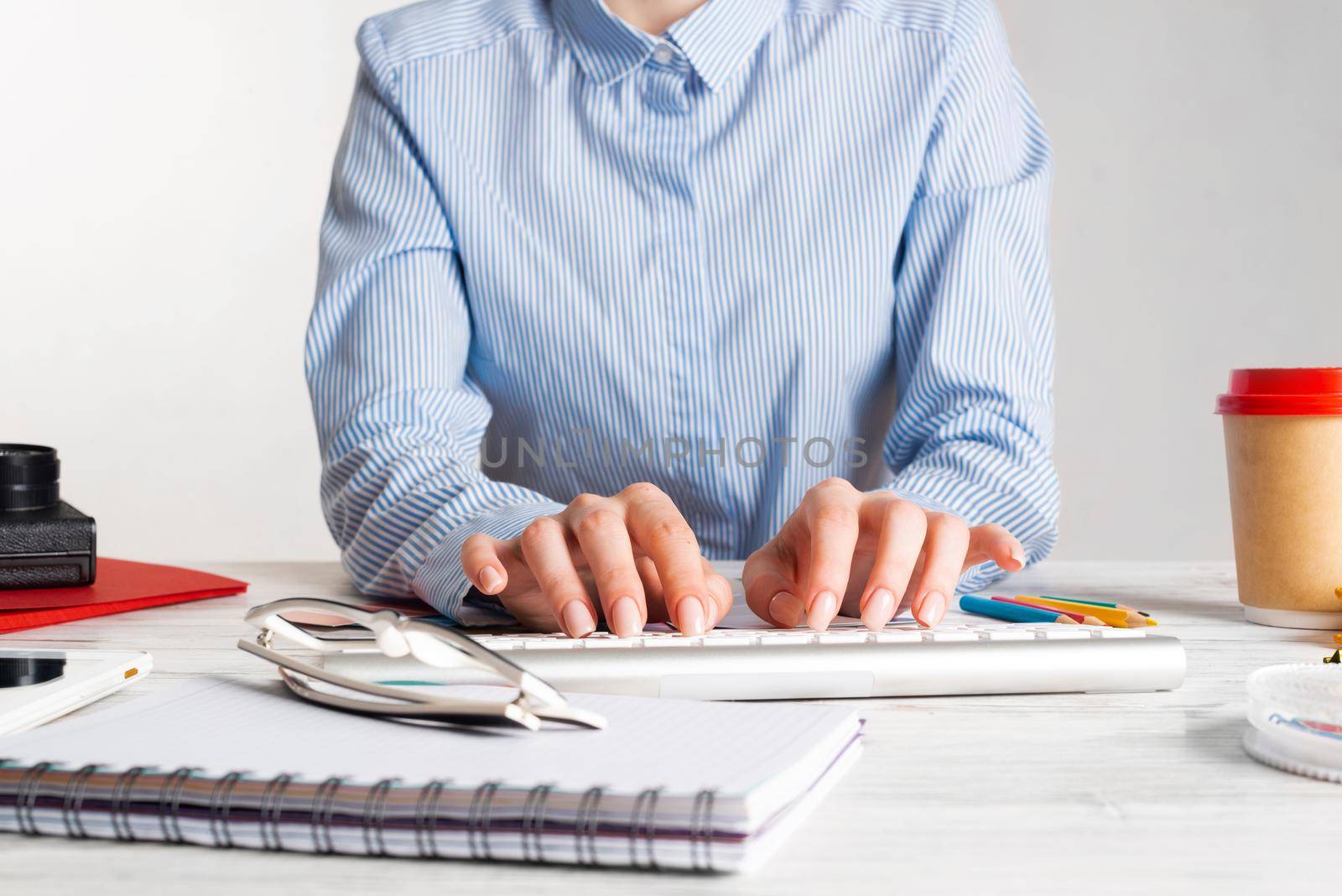 Woman consultant typing on keyboard. Creative workspace with color swatches, notebook and cup of coffee. Professional product designing. Coloristics and product branding in visual design studio.