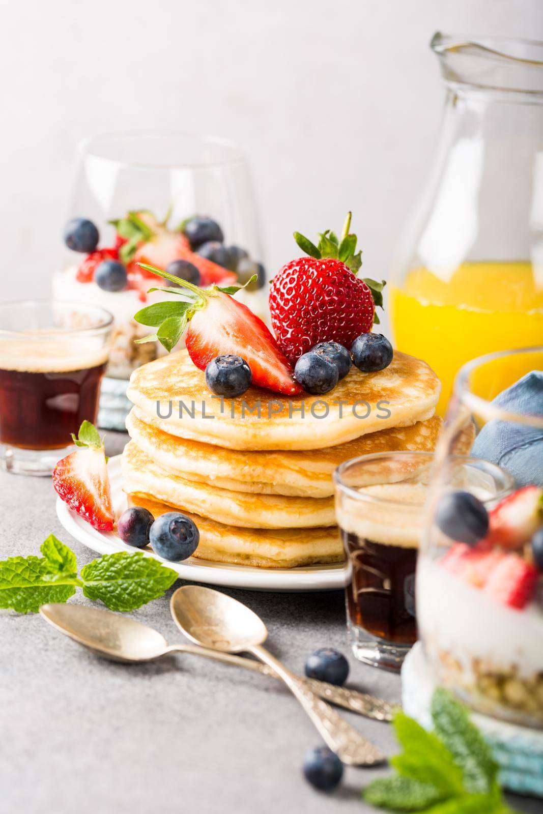 Breakfast composition with fresh pancakes and berries on light gray concrete background. Healthy food concept with copy space.