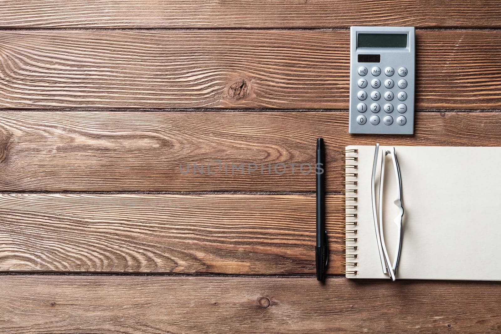 Still life of accountant vintage workspace with office accessories. Flat lay old hardwood desk with notepad, pen and calculator. Accounting and banking services. Finance and investment concept.