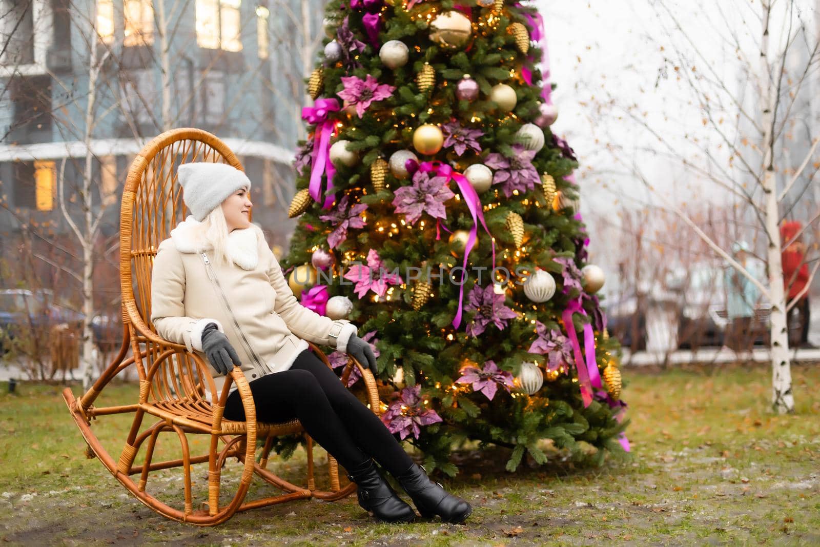 woman and photo zone christmas tree and rocking chair on the street