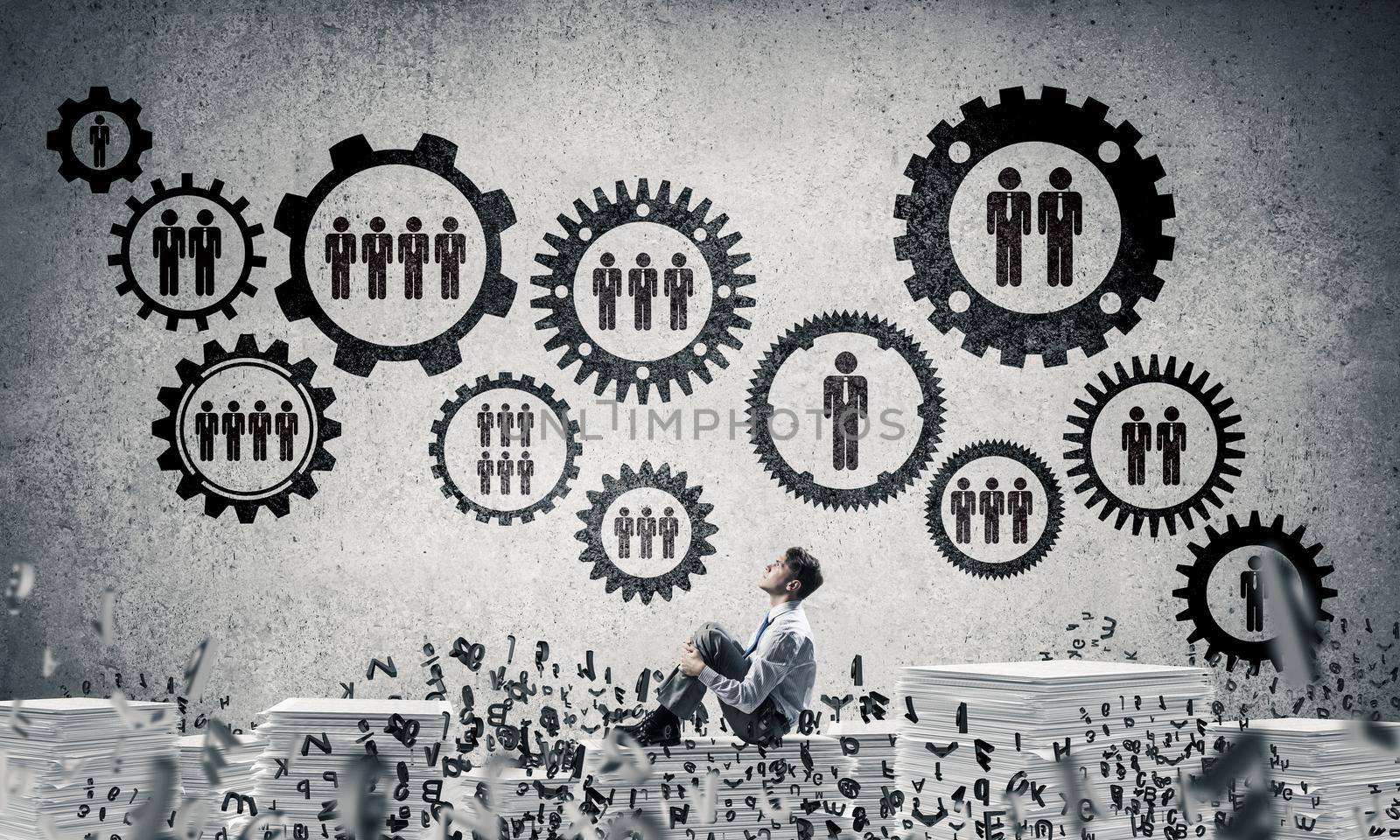 Businessman looking away while sitting on pile of documents among flying letters with social gear structure on background. Mixed media.