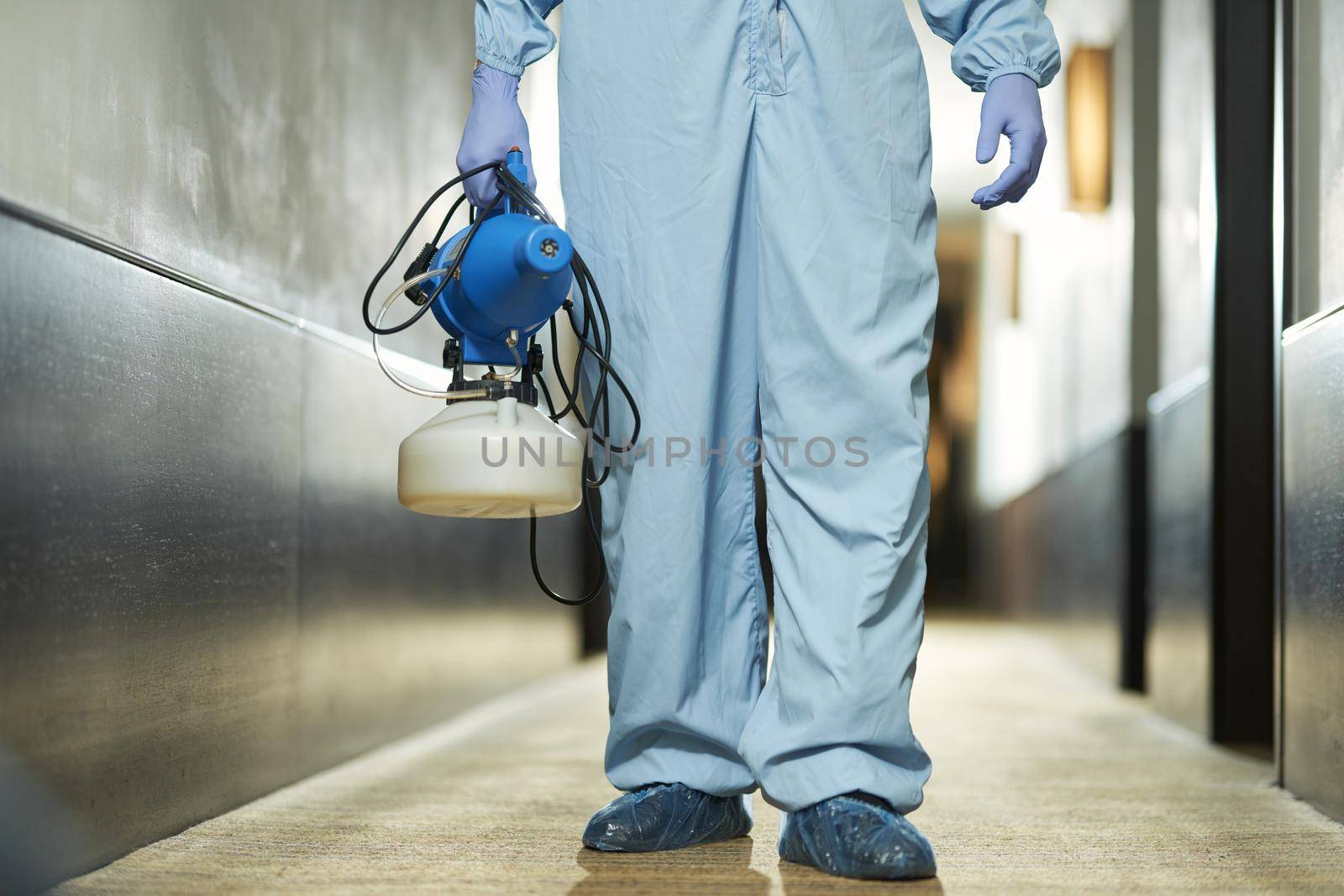 Cropped photo of man using sprays for remove bacteria from the surface at the hotel. Coronavirus and quarantine concept