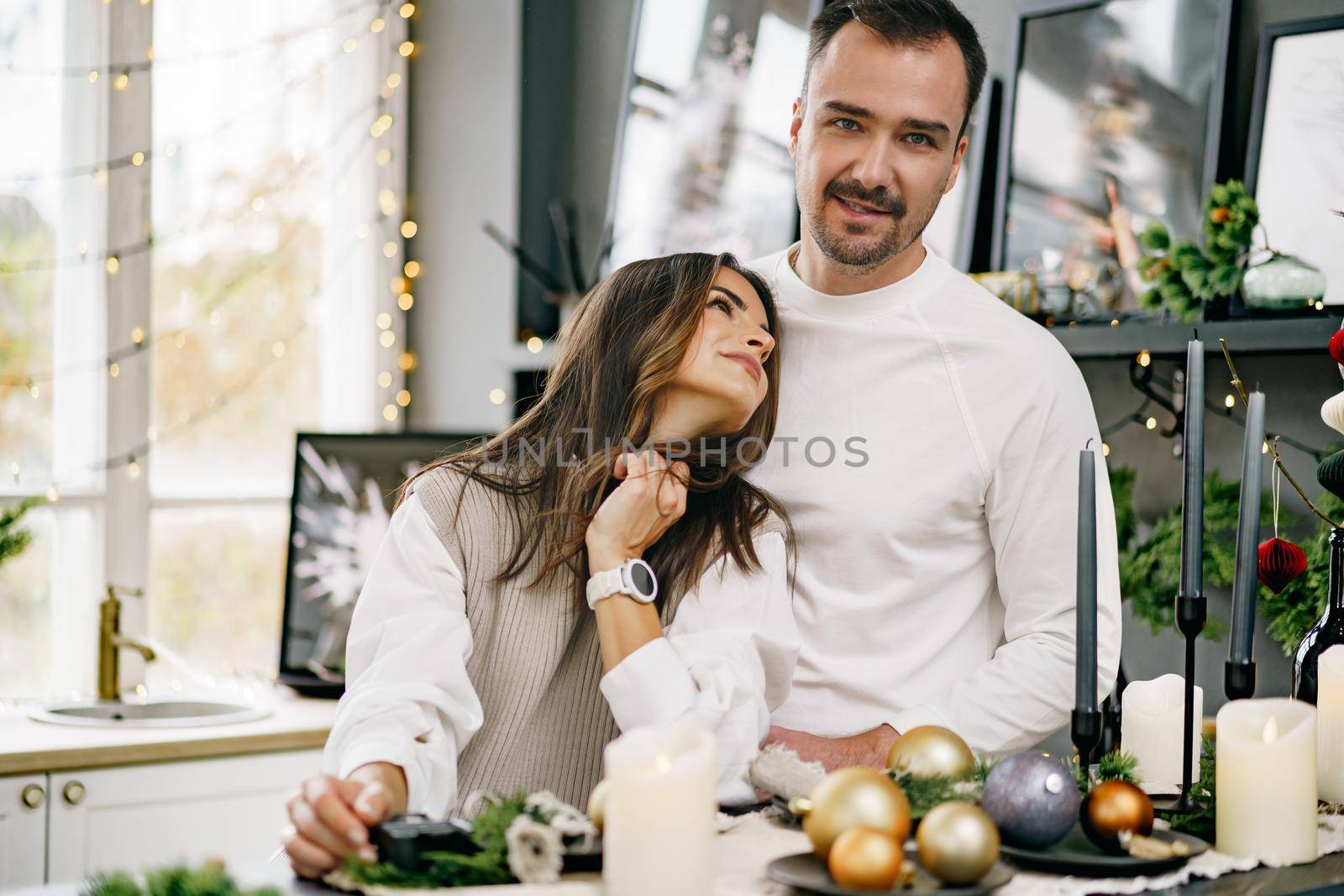 Young loving couple having good time at Christmas morning in decorated kitchen