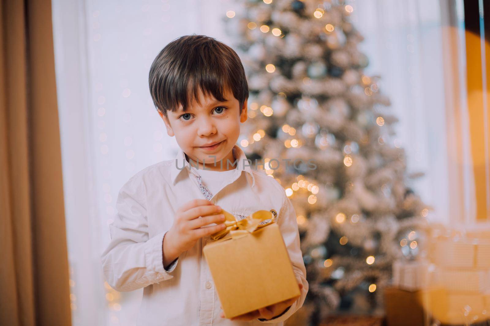 A boy with a New Year's gift under the tree lifestyle. New Year and Christmas. Festive decoration. New Year's gift