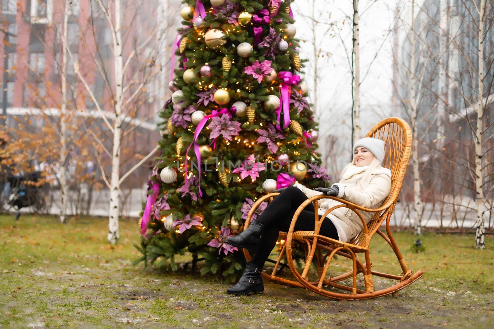 woman and photo zone christmas tree and rocking chair on the street