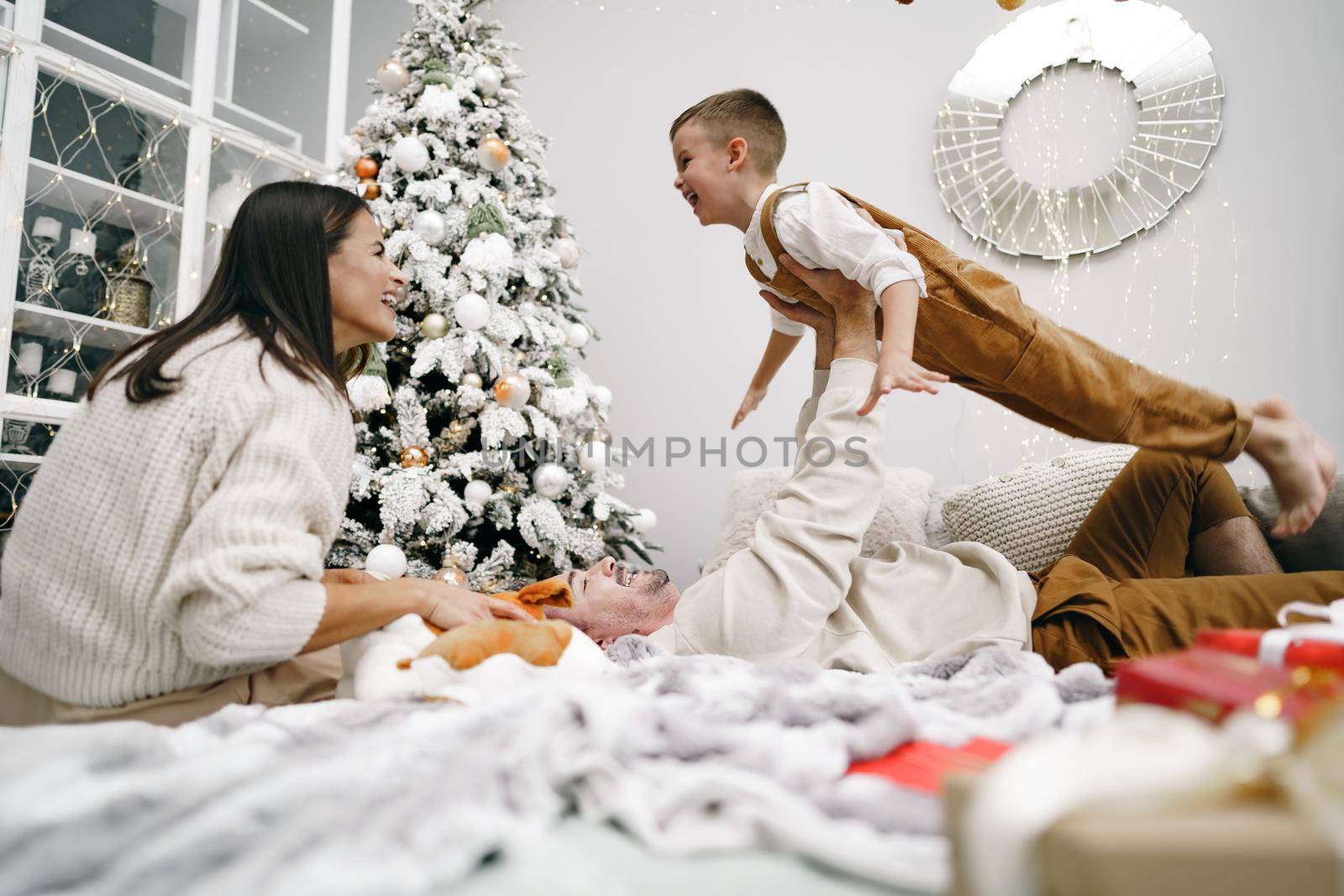 Mother, father and son having fun together on bed on Christmas day