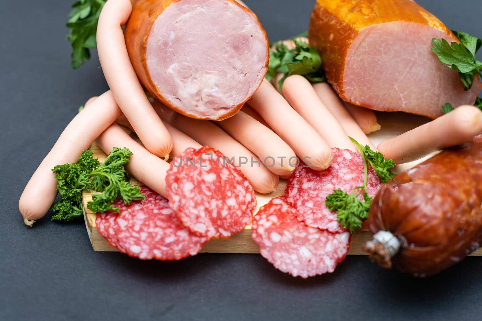 Different ham and salami with herbs on a dark background