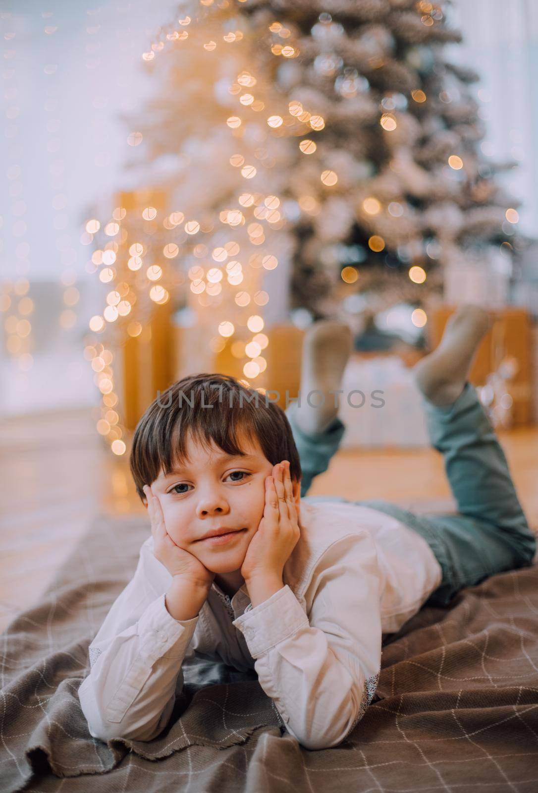 The boy is lying under the New Year tree lifestyle. New Year and Christmas. Festive decoration.