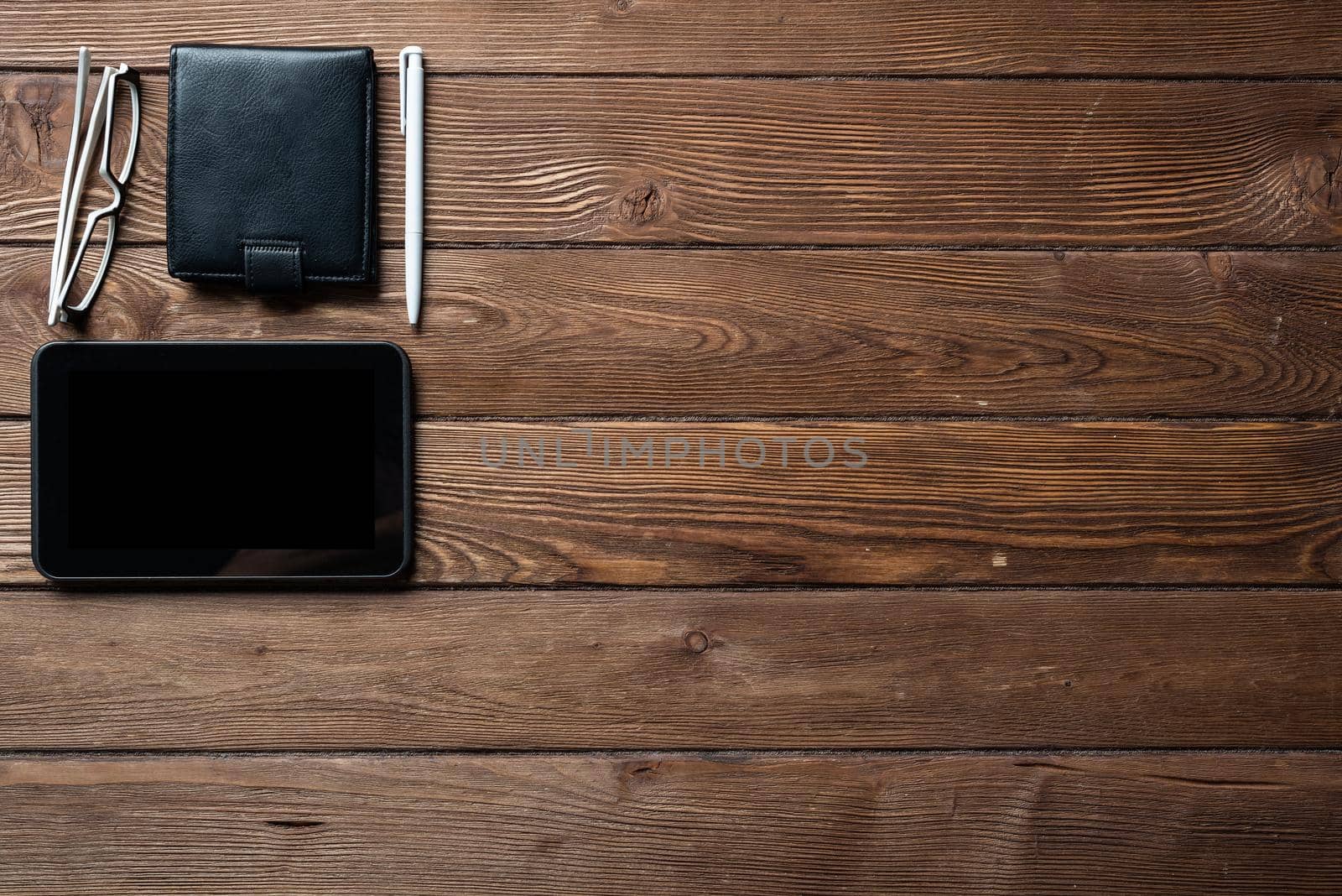 Still life of office workspace with supplies. Flat lay old hardwood desk with black leather wallet and tablet computer. Online shopping and payment. Creativity and innovation concept with copy space