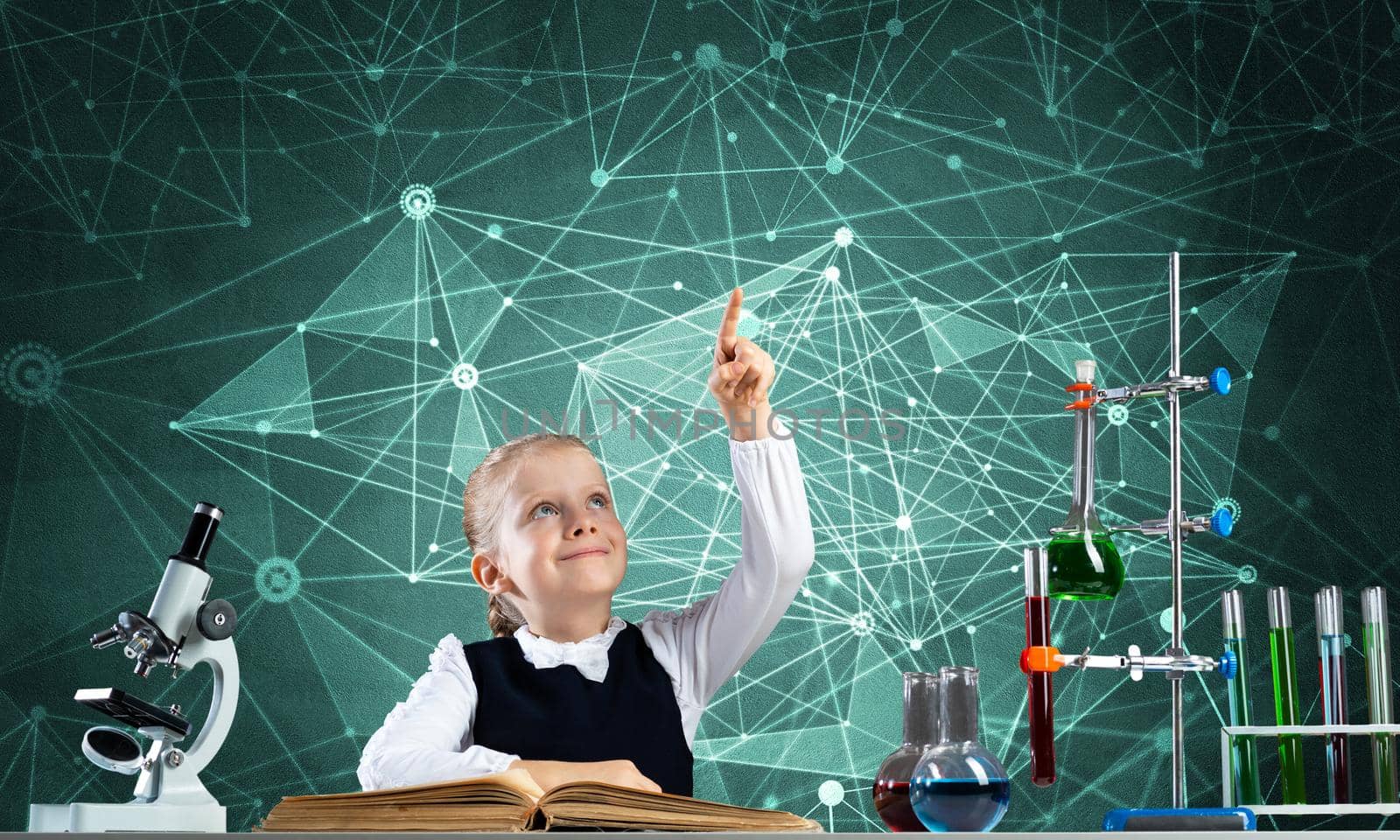 Little girl scientist sitting at desk in elementary science class. Research and education in school. Chemical laboratory with microscope, flasks and test tubes. Happy schoolgirl finger pointing up