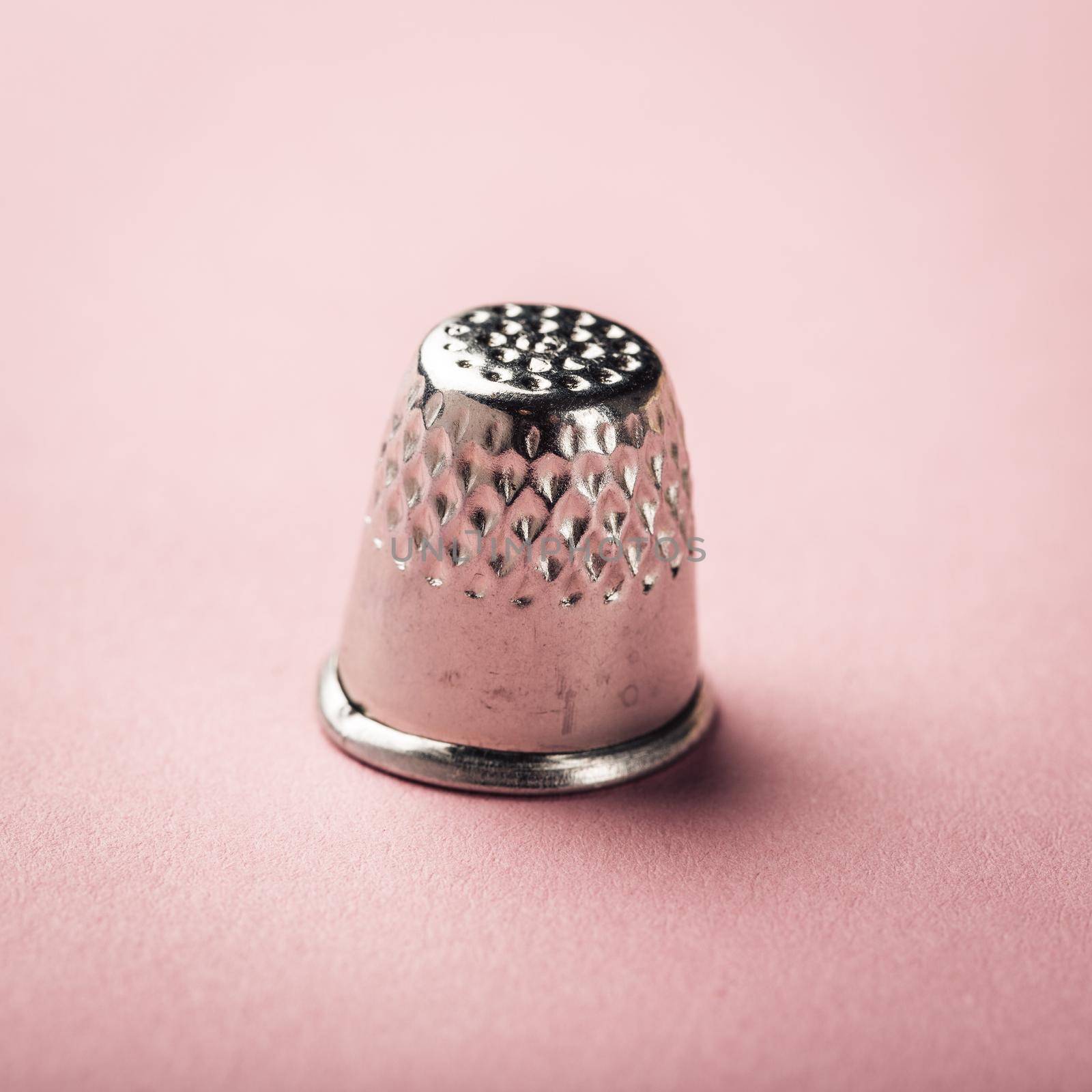 Vintage silver metal thimble on pink background