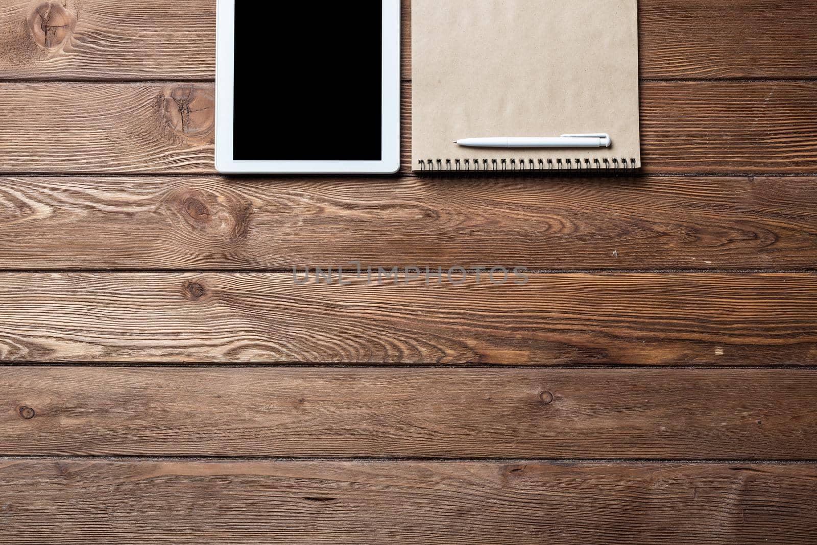 Top view of well organized home office workplace. Spiral notepad, pen and tablet computer on white surface. Education, creativity and working concept. Minimalist business design with copy space.