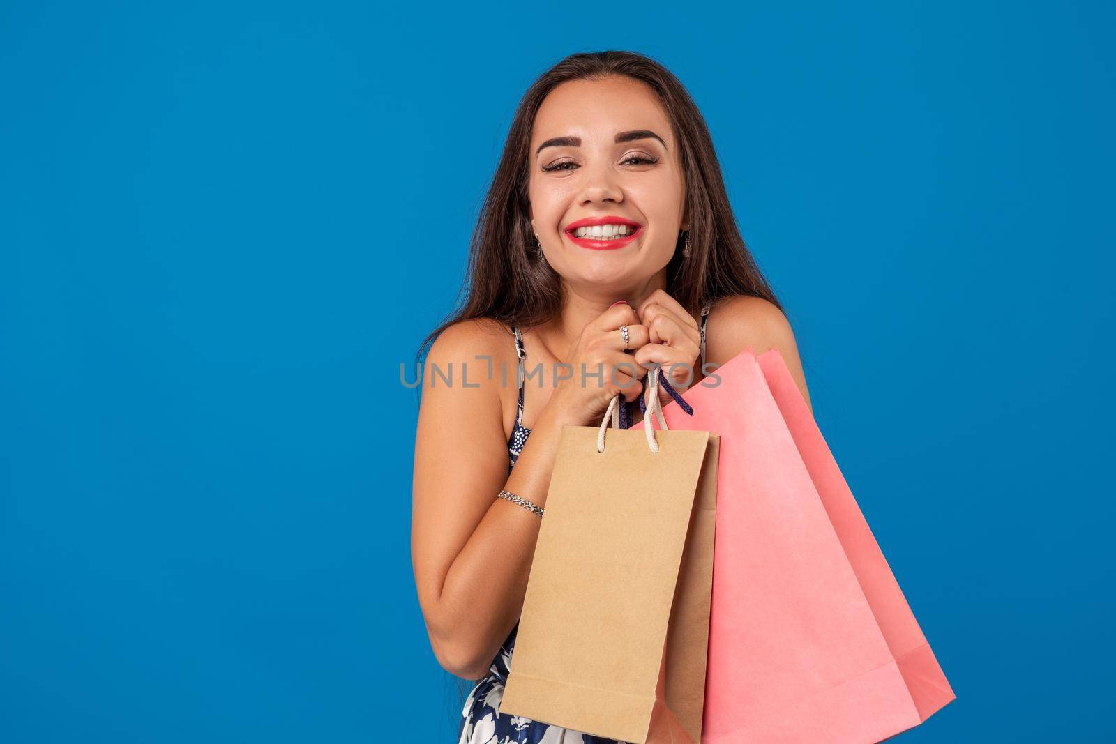 Photo of beautiful young woman with shopping bags on the wonderful blue background. The concept of shopping