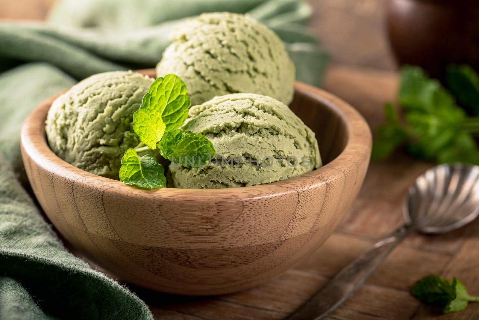 Mint ice cream scoops in wooden bowl on old wooden table background. Homemade summer food concept with copy space.