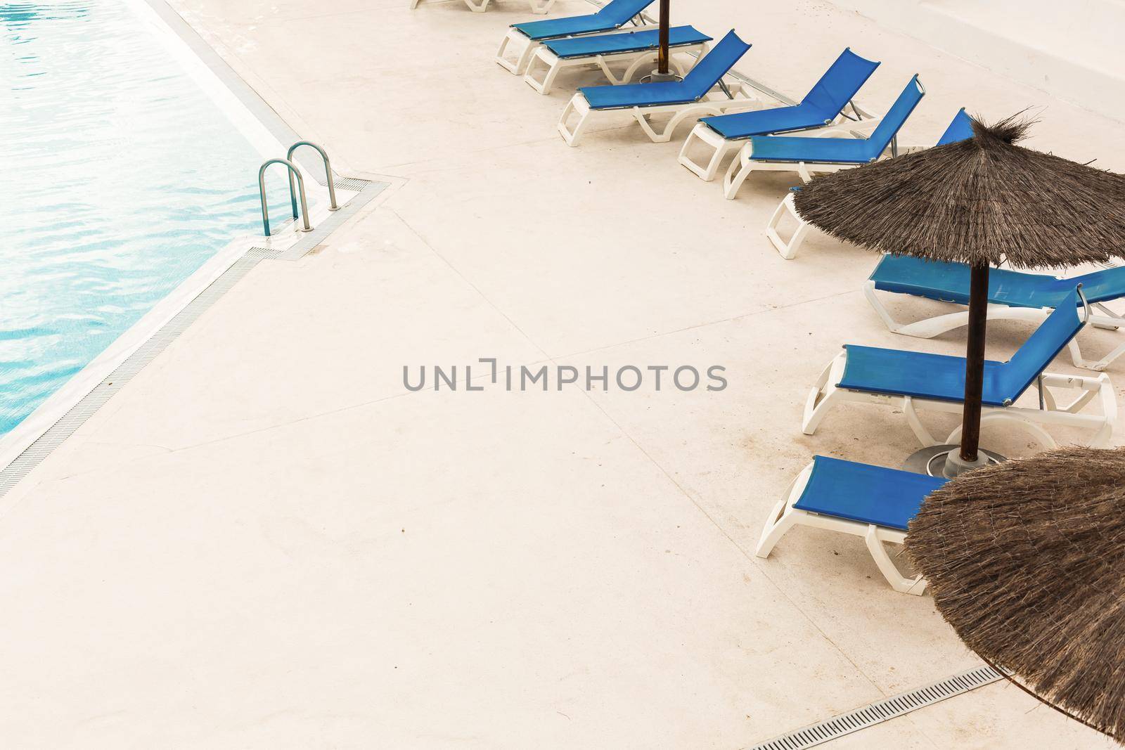 Hotel swimming pool with empty sun loungers.